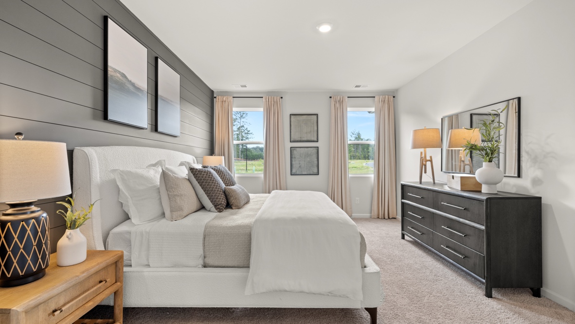 Side view of primary bedroom with earthy tones, light pink curtains, and deep wood accents.