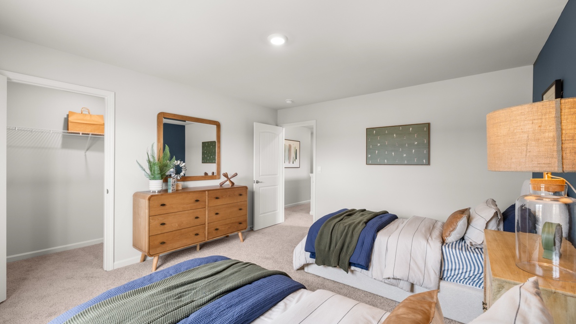 Bedroom 3 with two twin beds, walk-in closet with wire rack shelving, and dresser below a mirror