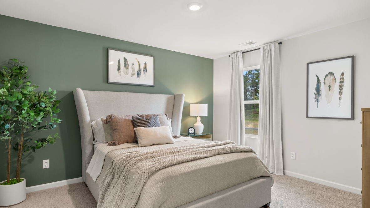 Full bedroom 2 with tall green plans, feather artwork, and large queen sized bed