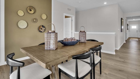 dining room table with modern art design and hallway to front door.