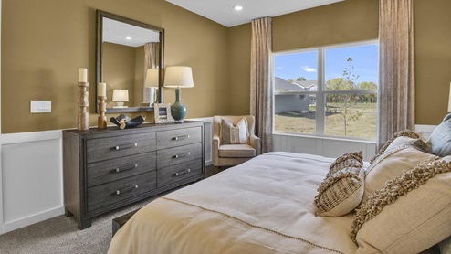 Side view of Primary bedroom with dresser and comfortable chair.