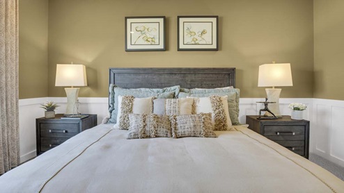 Full shot of beautiful farmhouse style primary bed with matching bedside table.