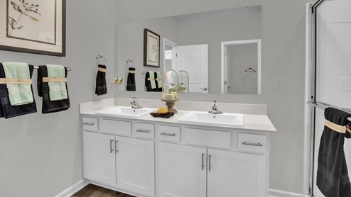 Primary bathroom with large mirror, white storage cabinets, and dual vanity sinks.