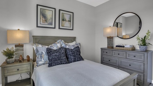 front bedroom bed with dresser and bed side table decorated.