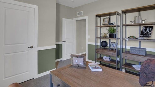 Bedroom shown as dayton themed office with desk and storage and display shelves.