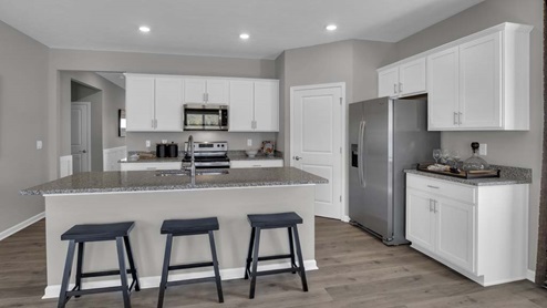 Full kitchen with island, applainces, and white cabinets.