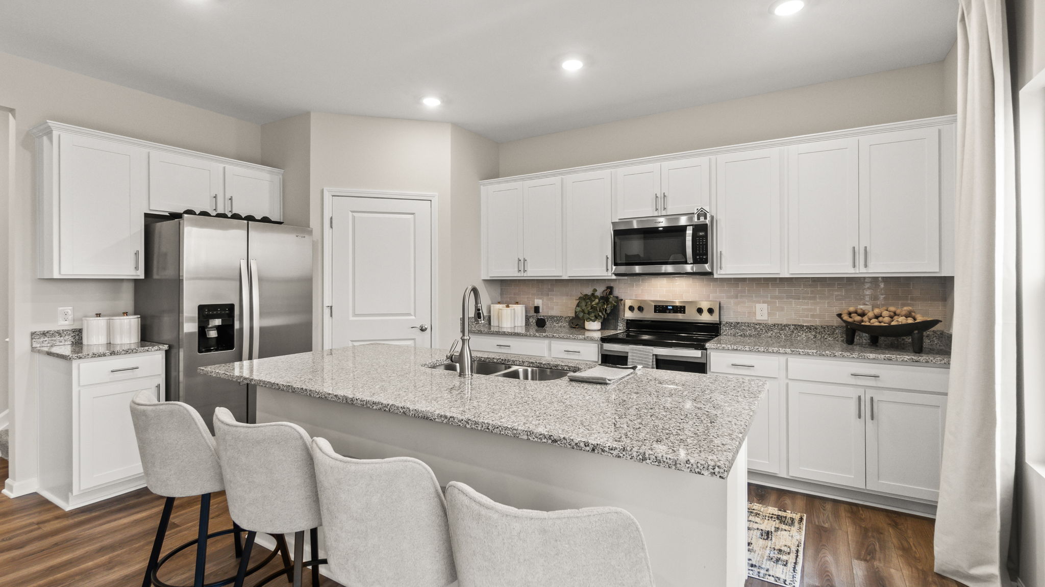 Three-quarter perspective of kitchen with granite countertops, appliances, and white elkins cabinetry.