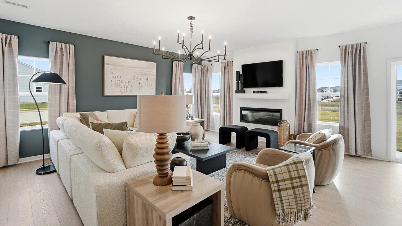 Primary bedroom with a brown upholstered bed, white bedding, blue throw, dark dresser, round mirror, and large windows.