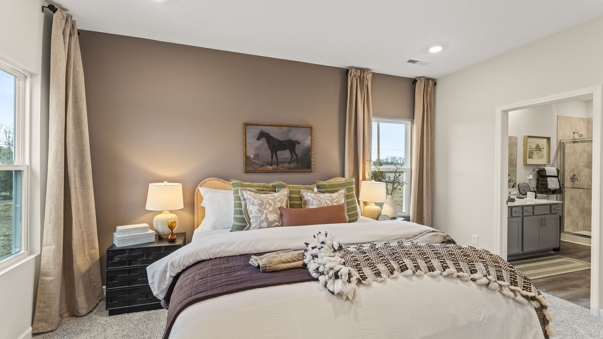 Three-quarter angle of bed with comforter, nightstands, and view of primary bathroom.