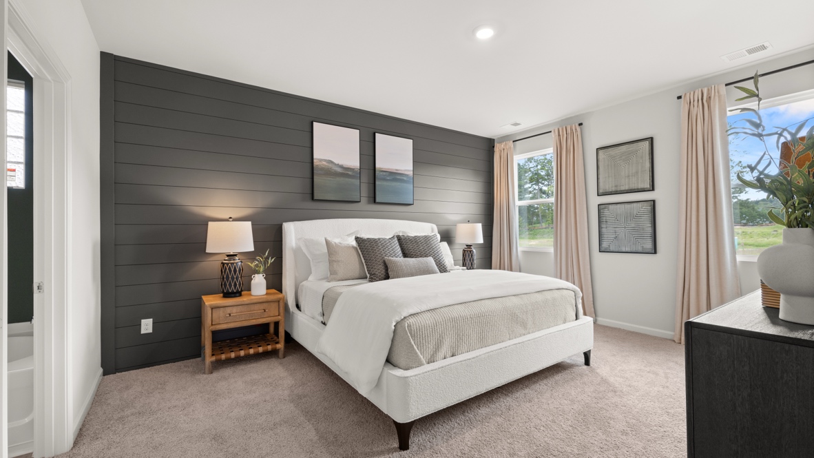 Full primary bedroom with white and brown bedding, brown nightstand, back wall with wood board backdrop, and abundant natual light.