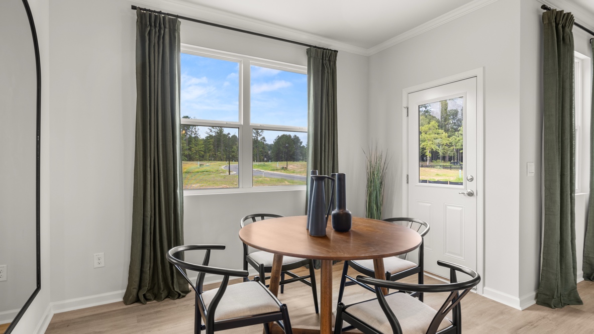 Dining area with olive green curtains and brown dining table adjacent to backdoor