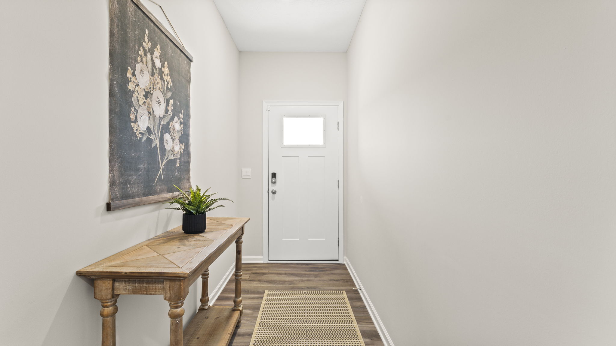 Hallway looking at front door with art piece and side-table