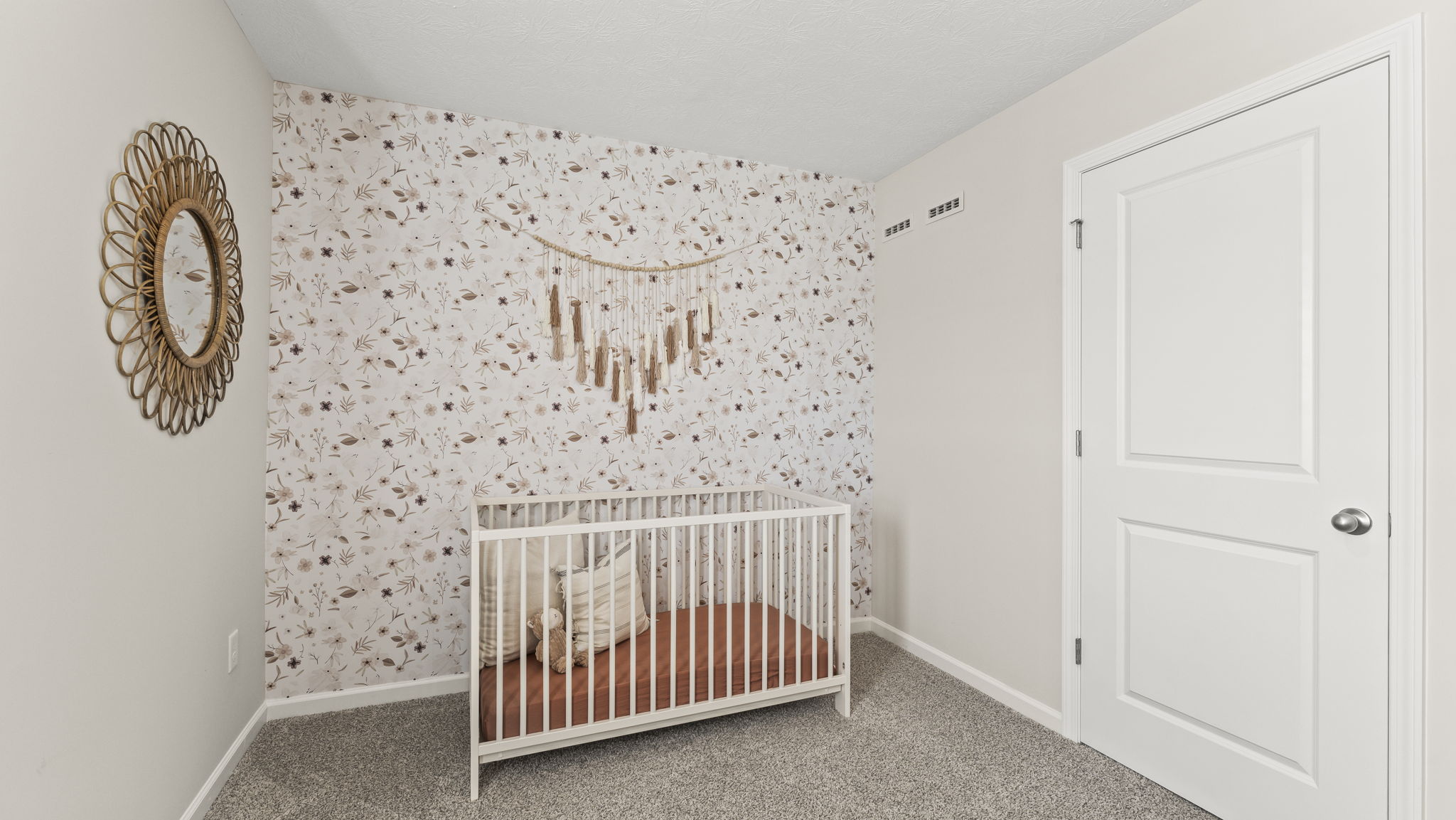 Bedroom configured as a nursery with wallpaper, crib, and soothing decorations
