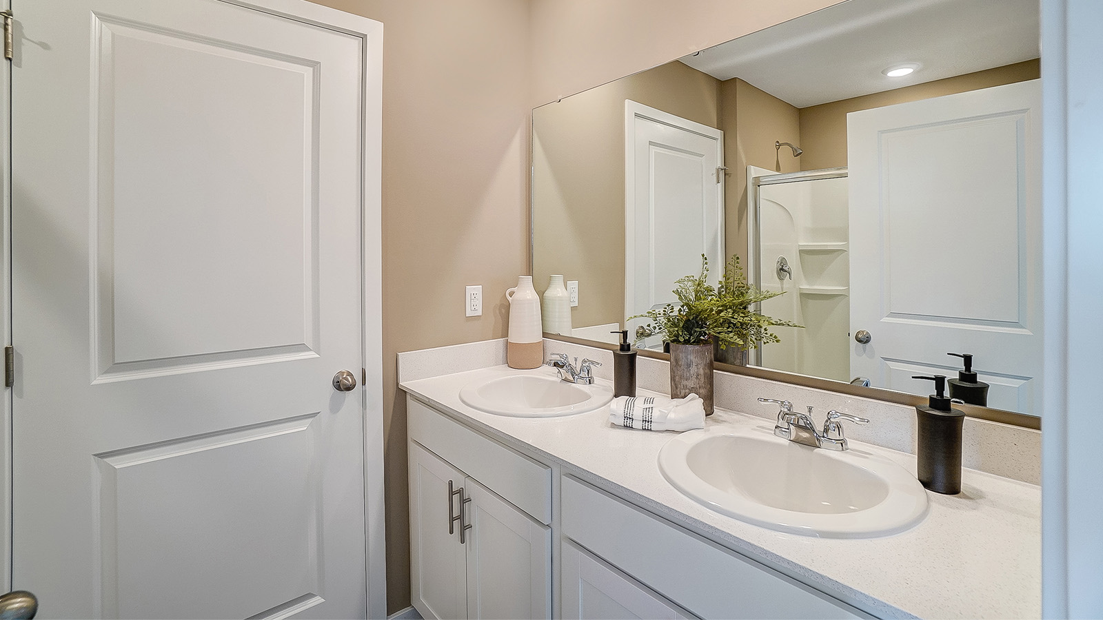 Dual vanity sinks in the primary bedroom with a large mirror.