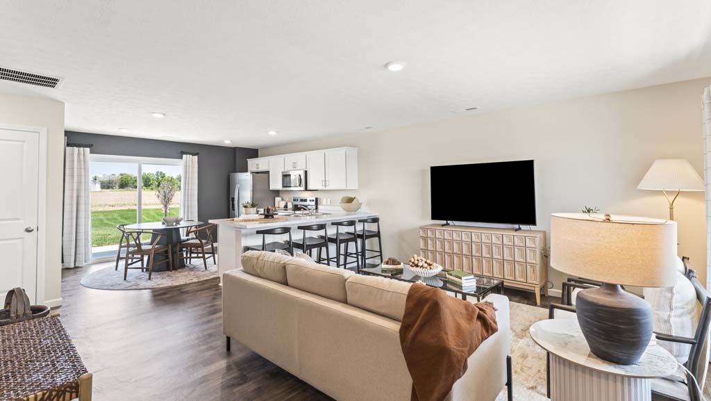 Living room with contemporary furniture with view of kitchen countertops and stainless steel appliances.