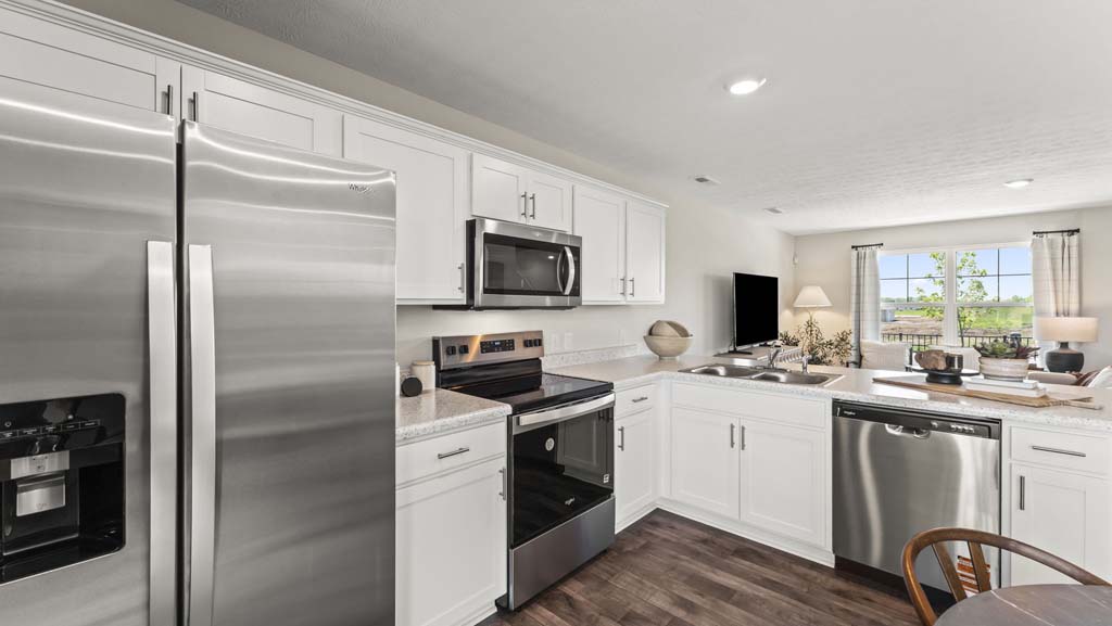 Quarter angle of stainless steel kitchen fridge, cabinetry, oven, microwave, and dishwasher.