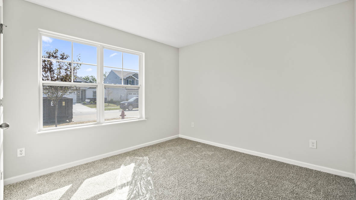 Perspective of bedroom looking at windows to the outside that has white walls and carpet