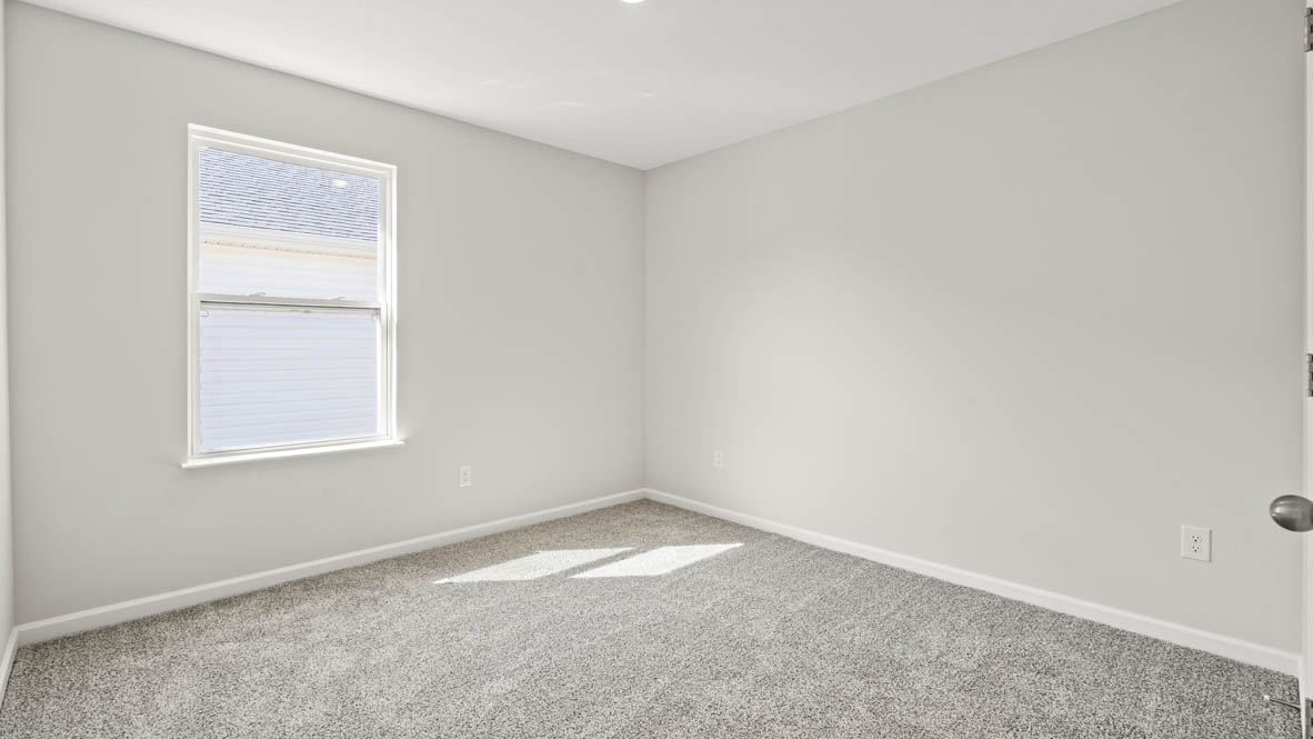 Perspective of bedroom looking at windows to the outside that has white walls and carpet