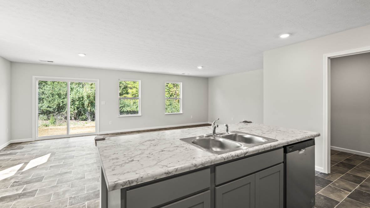 Kitchen island with laminate countertops with perspective of great room leading to the backyard