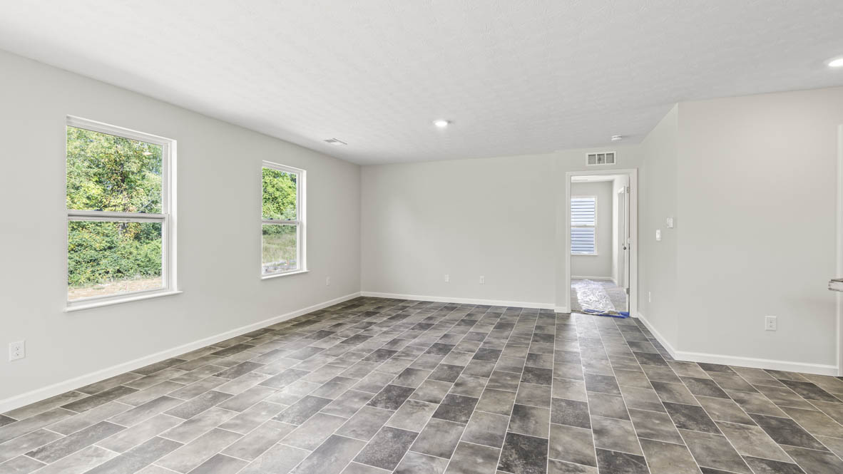 Great room with earthy-patterned flooring, two windows, and entrance into the primary bedroom