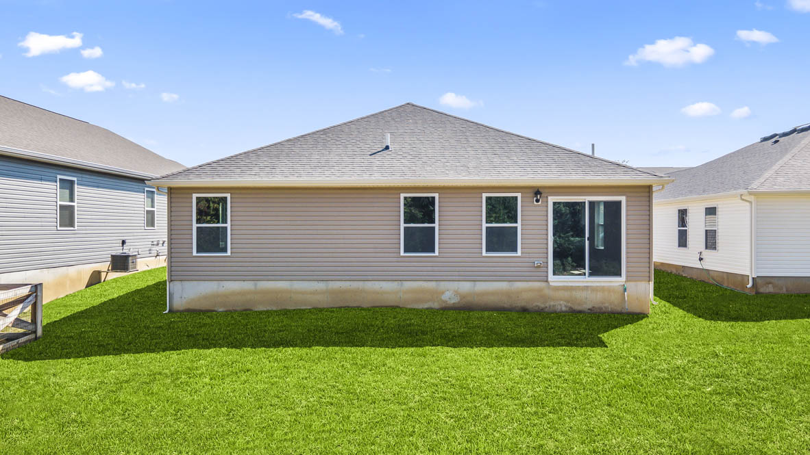 Rear of home with green grass, neutral tone paint, and sliding door