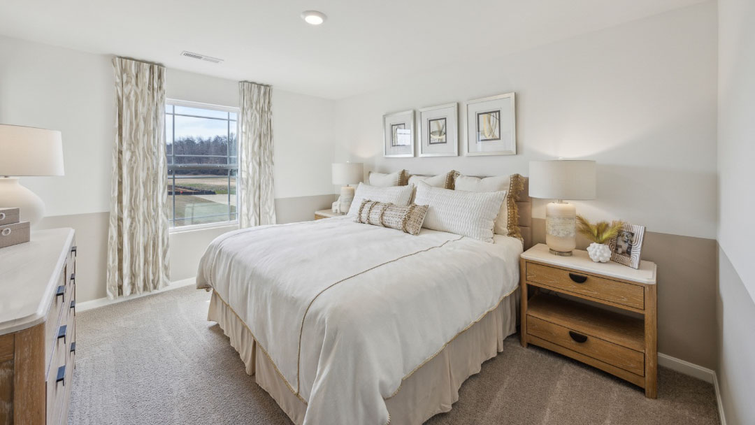 spacious bedroom with white and beige colored decor, featuring a wooden nighstand on each side of the bed, a large window, and a wooden dresser