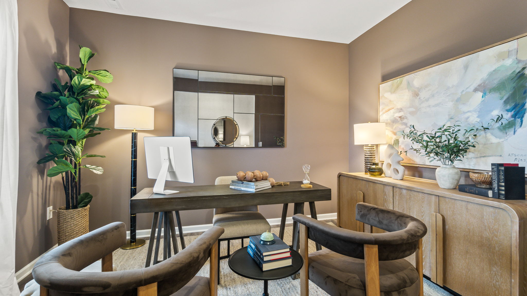 Flex room staged as an office with plan, table, chairs, and dresser with books and lamps.