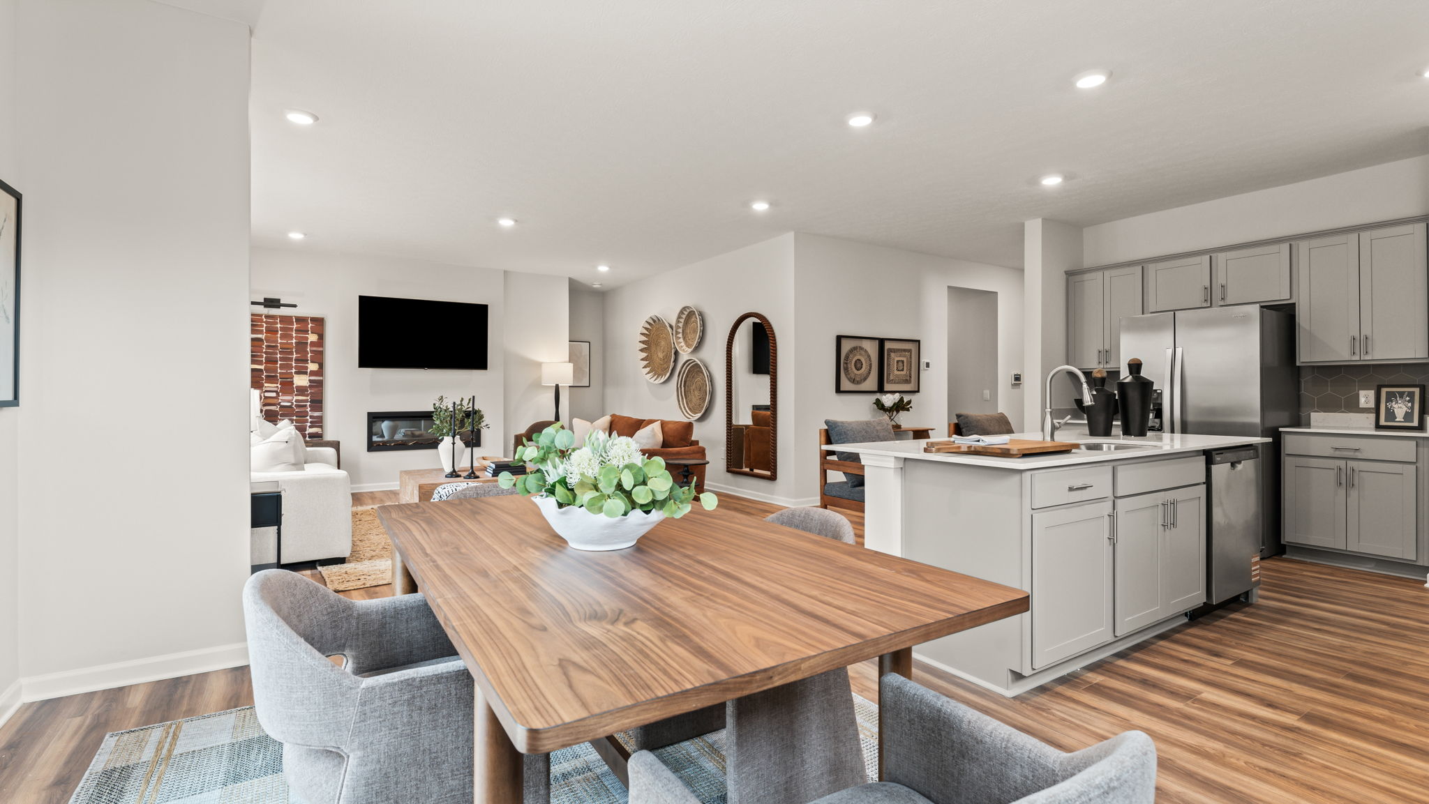 Full dining, kitchen, and livingroom area in a bright vibrant setting with abundant wood toned objects and contemporary art