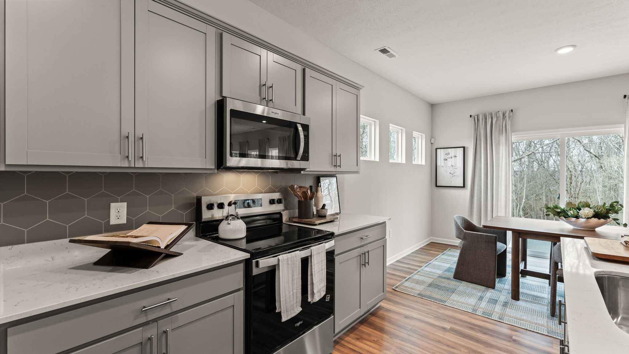 Kitchen with gray cabinetry, granite countertops, and stainless steel appliances.