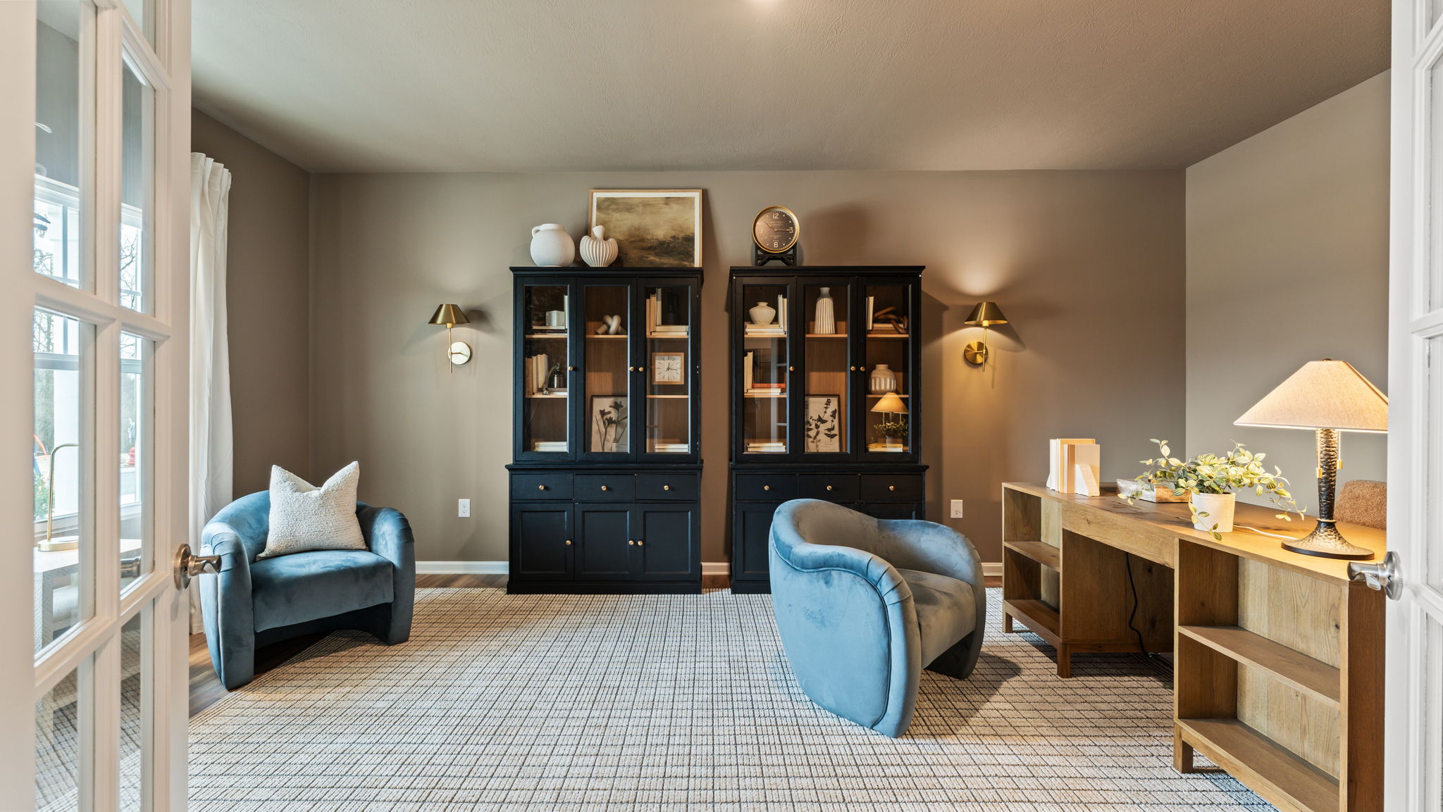 Flex room arranged as a warm office with dark bookcases, blue single-seater chairs, and brown wooden desk