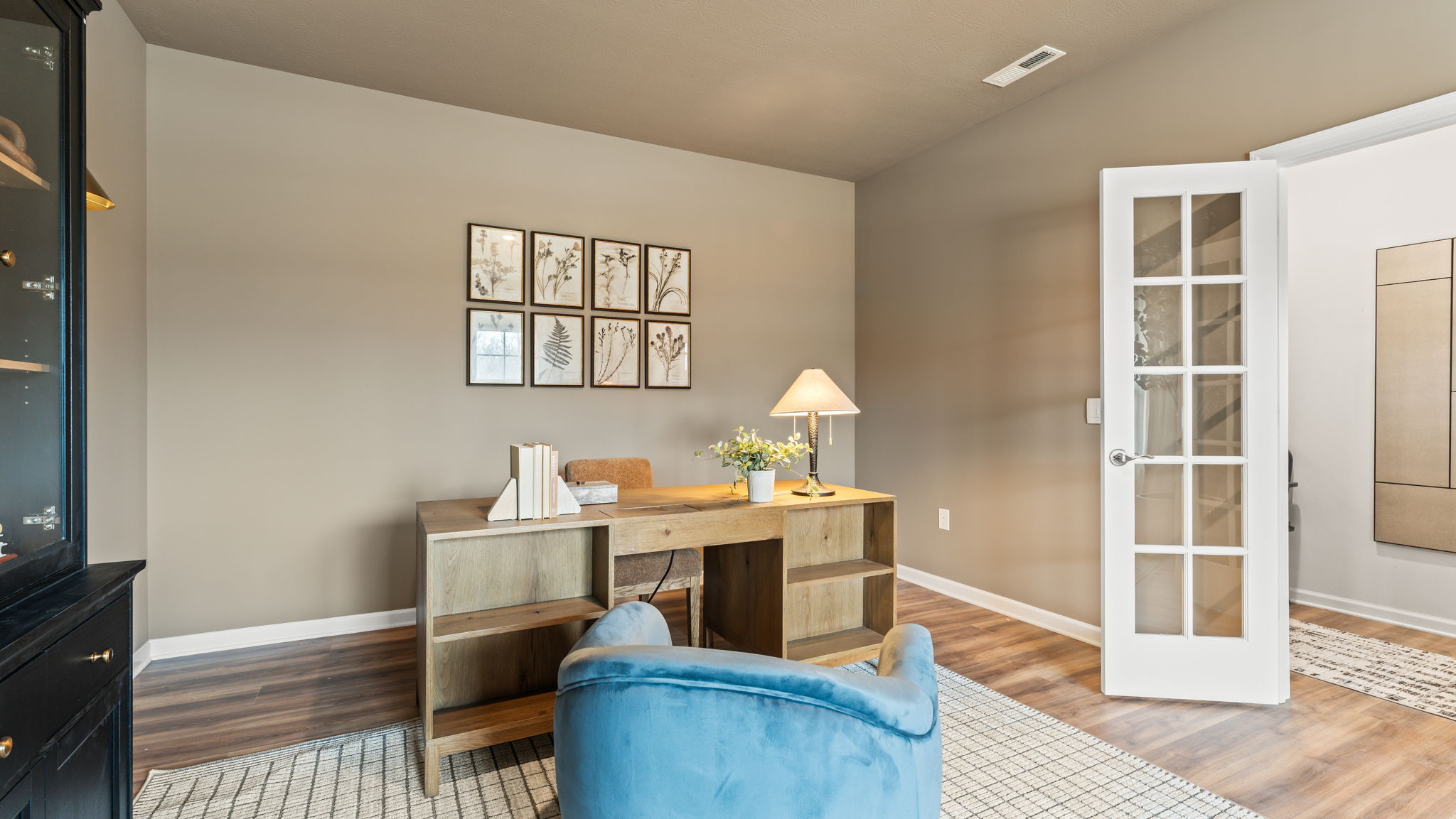 Office-space with wooden cabinets, desk, and sand colored wall