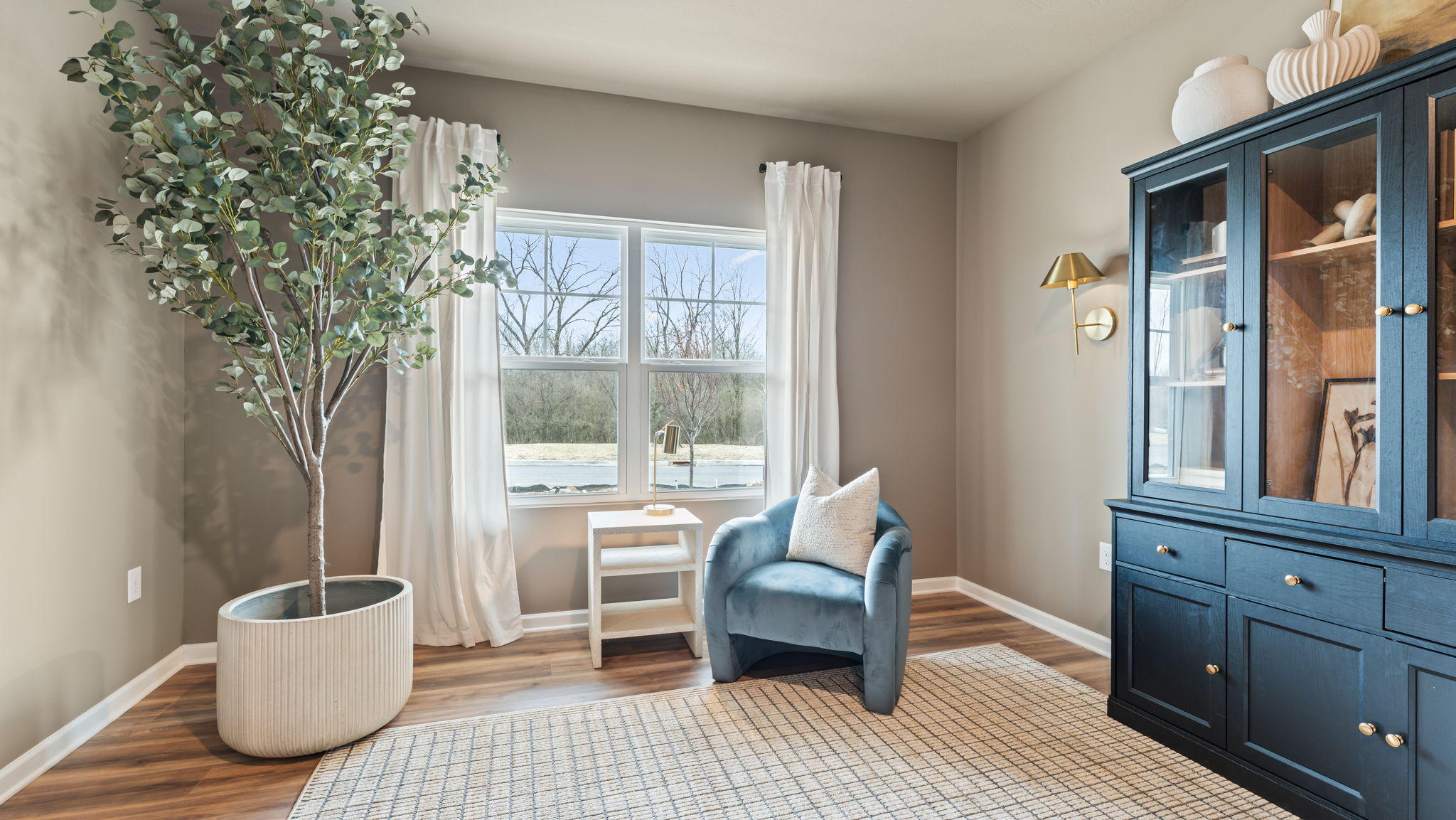 Open space of a flex room arranged as an office with light airty chairs, plans, and curtains adjacent to a deep dark colored bookcase