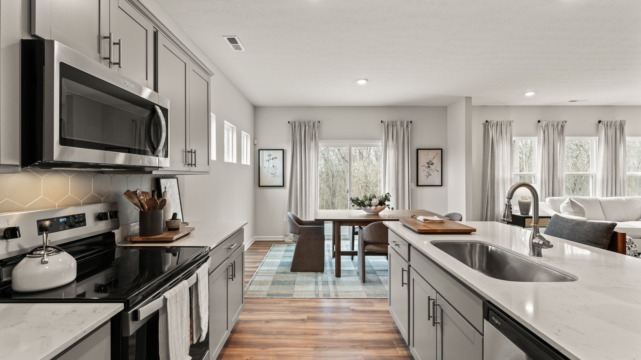 Side view of kitchen with dining area in the back, abundant natural light elevating the room to be warmer.