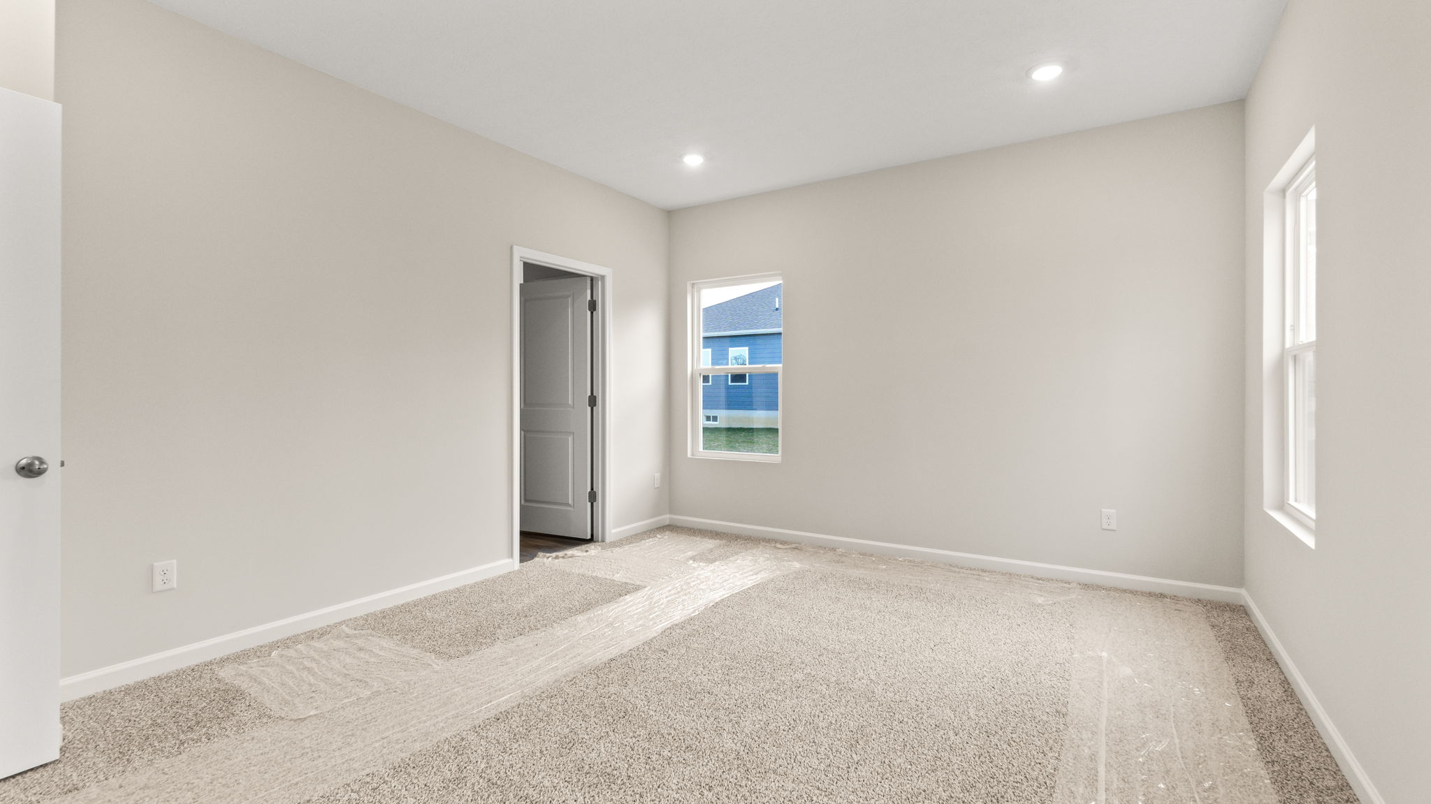 Carpeted primary bedroom with door to bathroom
