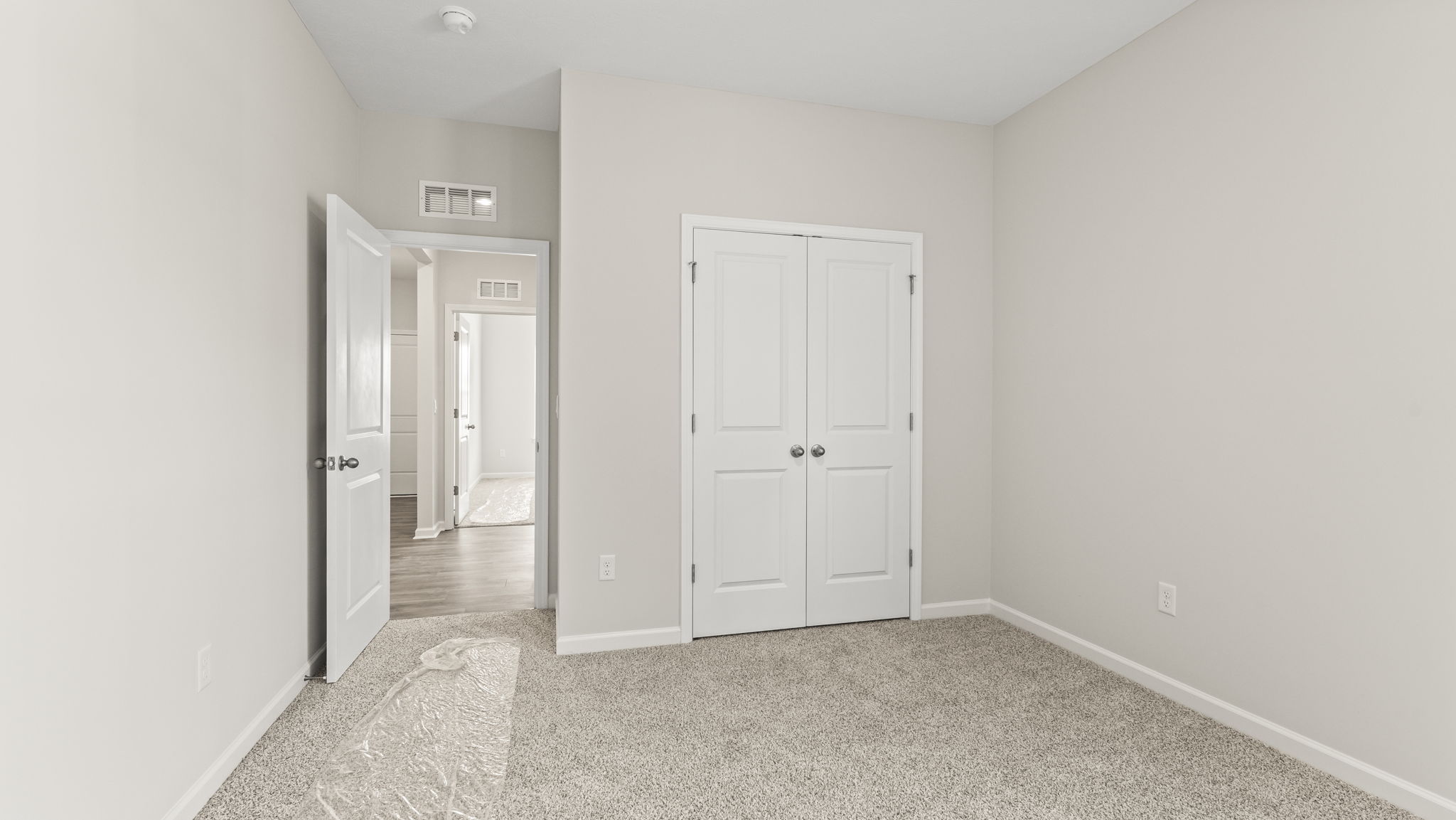 Carpeted bedroom with door to closet and another door to hallway