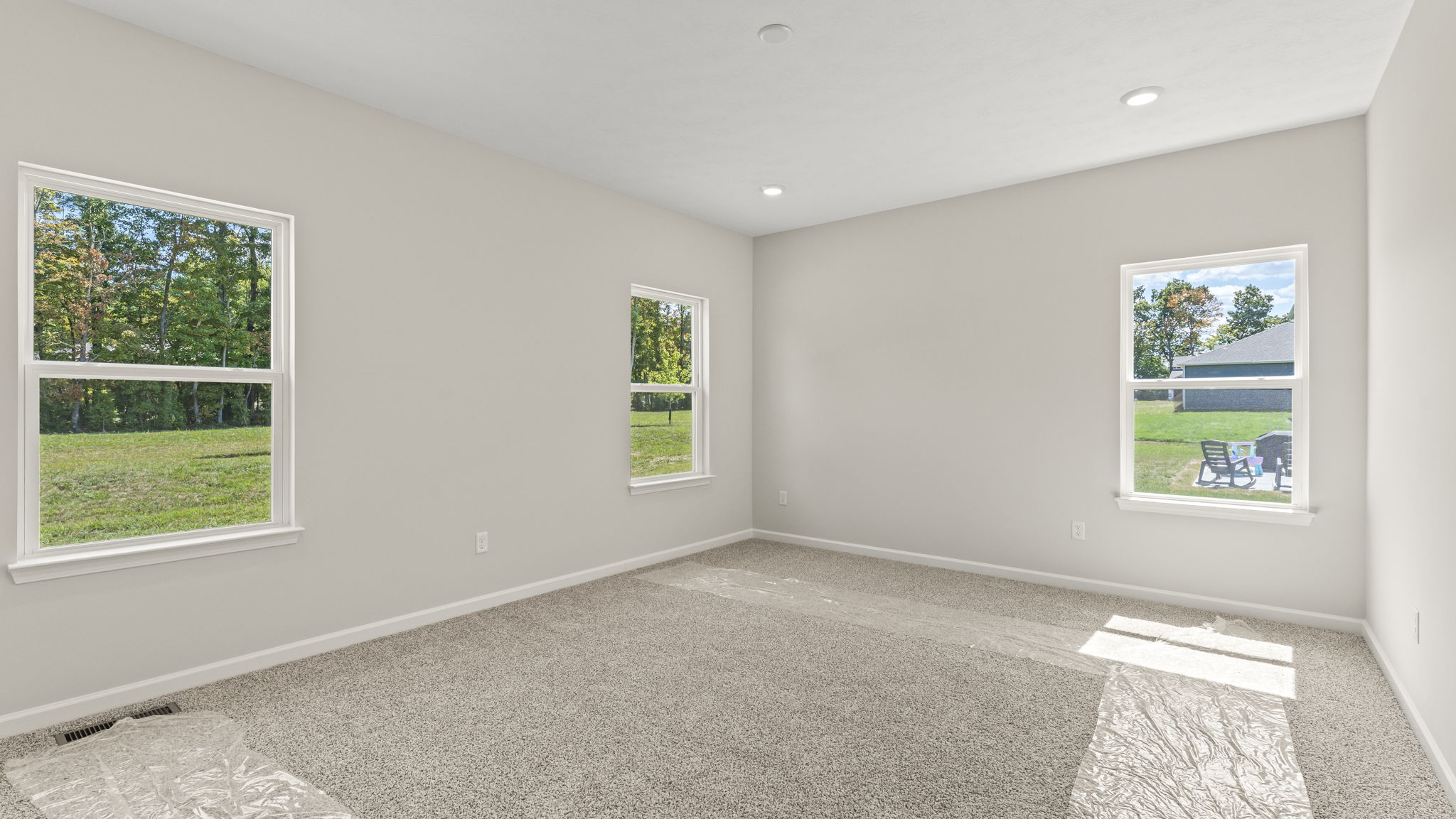 Primary bedroom with carpeted floors and 3 windows in frame