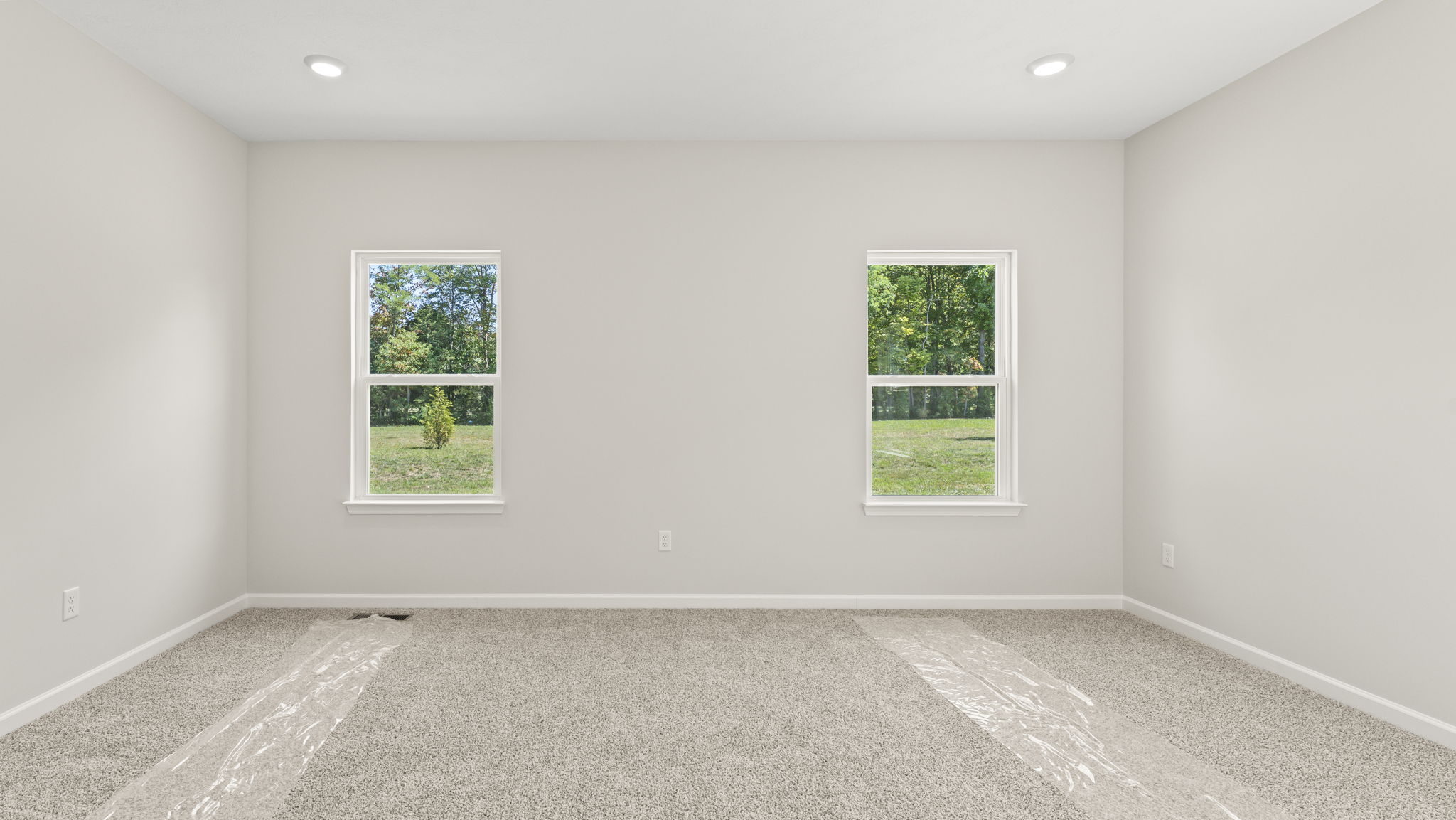 Primary bedroom with carpeted floors and 2 windows in frame