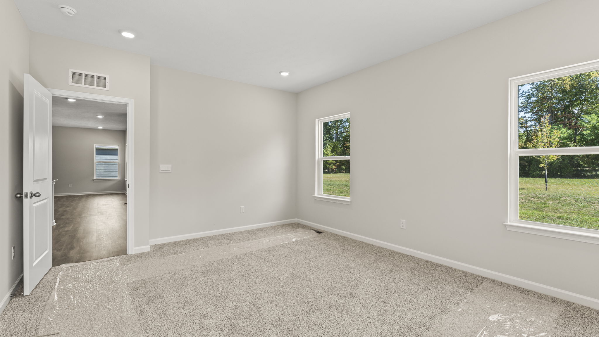 Primary bedroom with 2 windows and door to bathroom suite