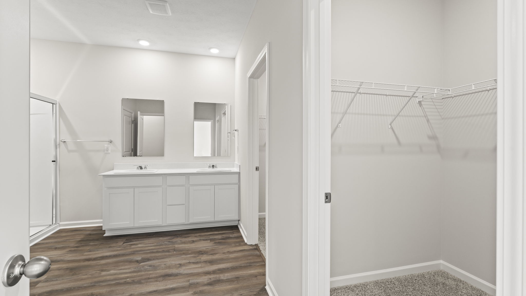 Doors of bathroom suite with view of sinks, mirrors, and walk-in closet