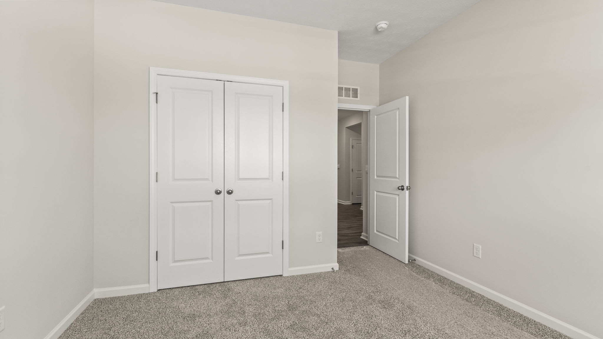 Carpeted bedroom with closet door and door to outside