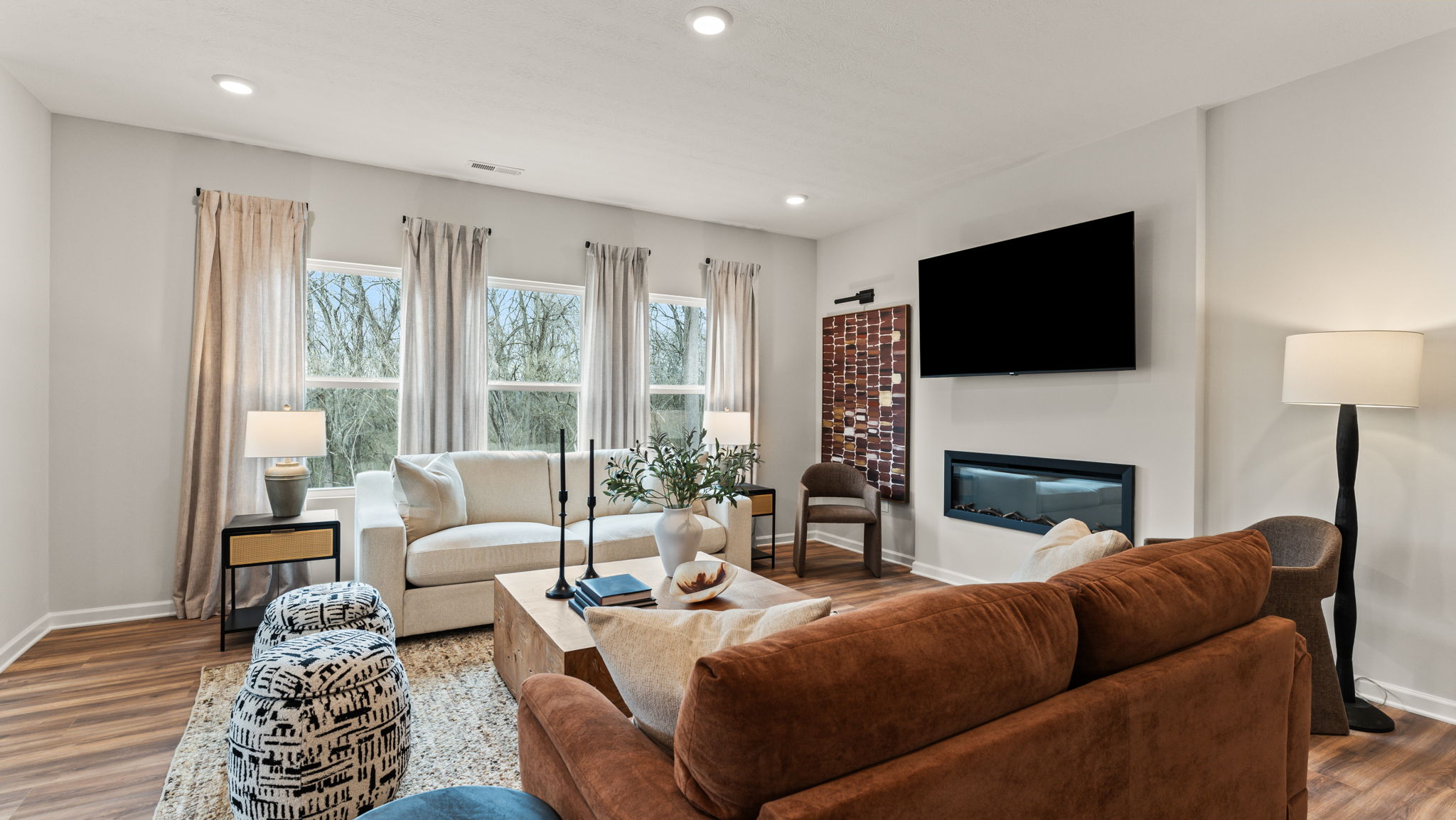 Three-quarter perspective of comfortable living room with natural lighting, earthy tones, and cozy couches and chairs.