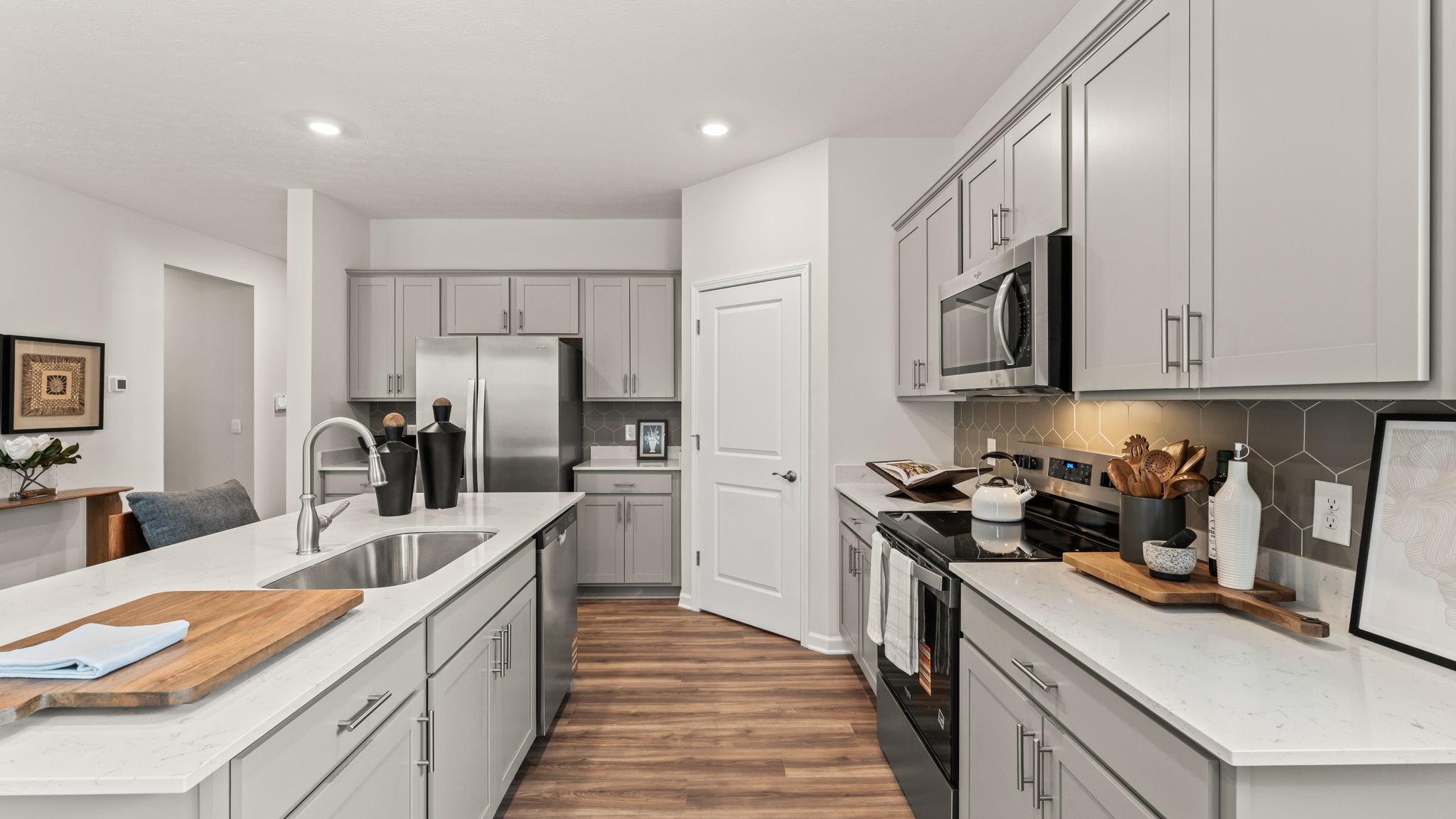 Side-view of well-appointed kitchen with hexagonal backsplash, Cutting boards, and stainless steel appliances.
