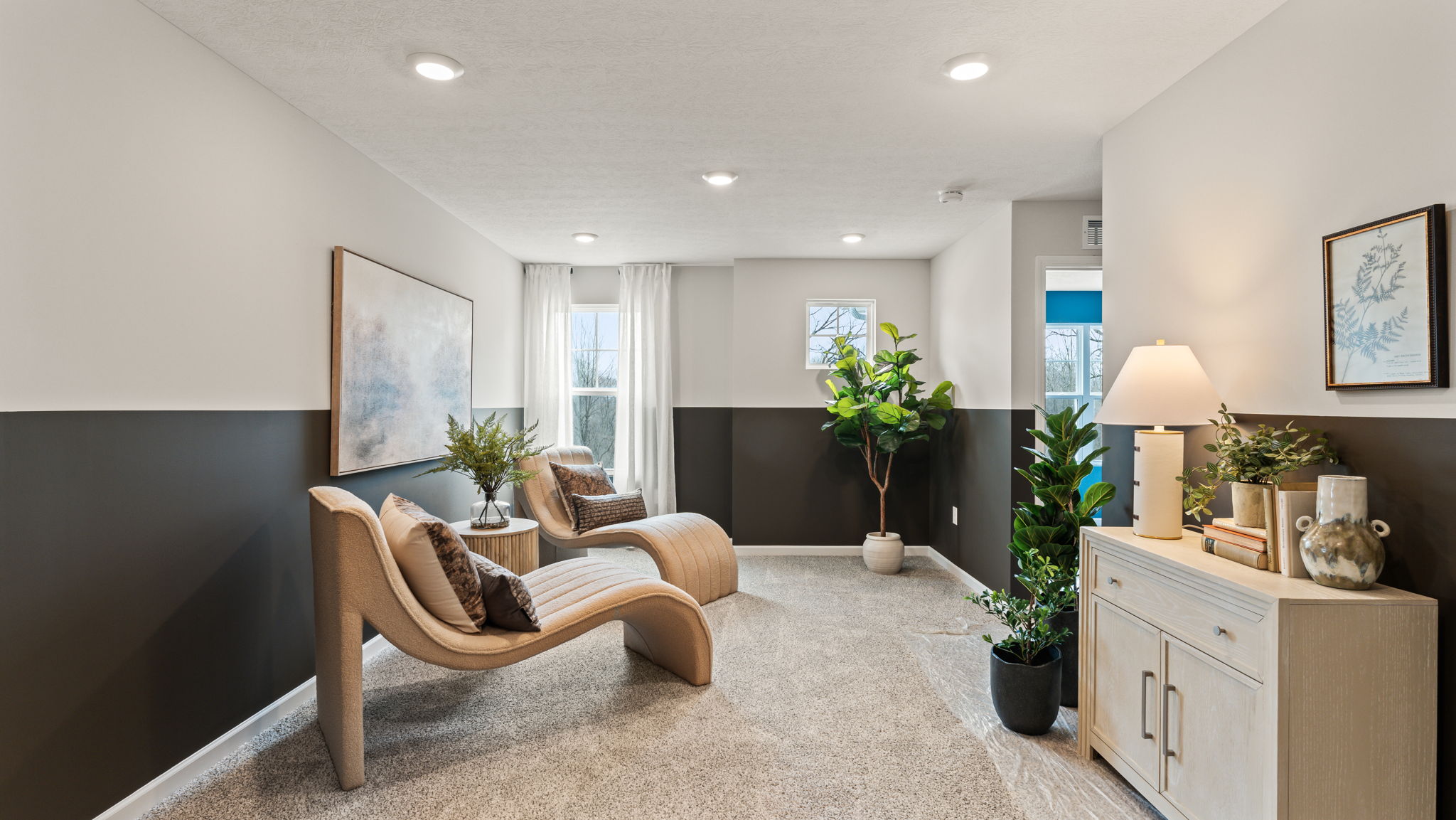 Two-tone black and white walls, laid-back white chairs, and pictures on wall
