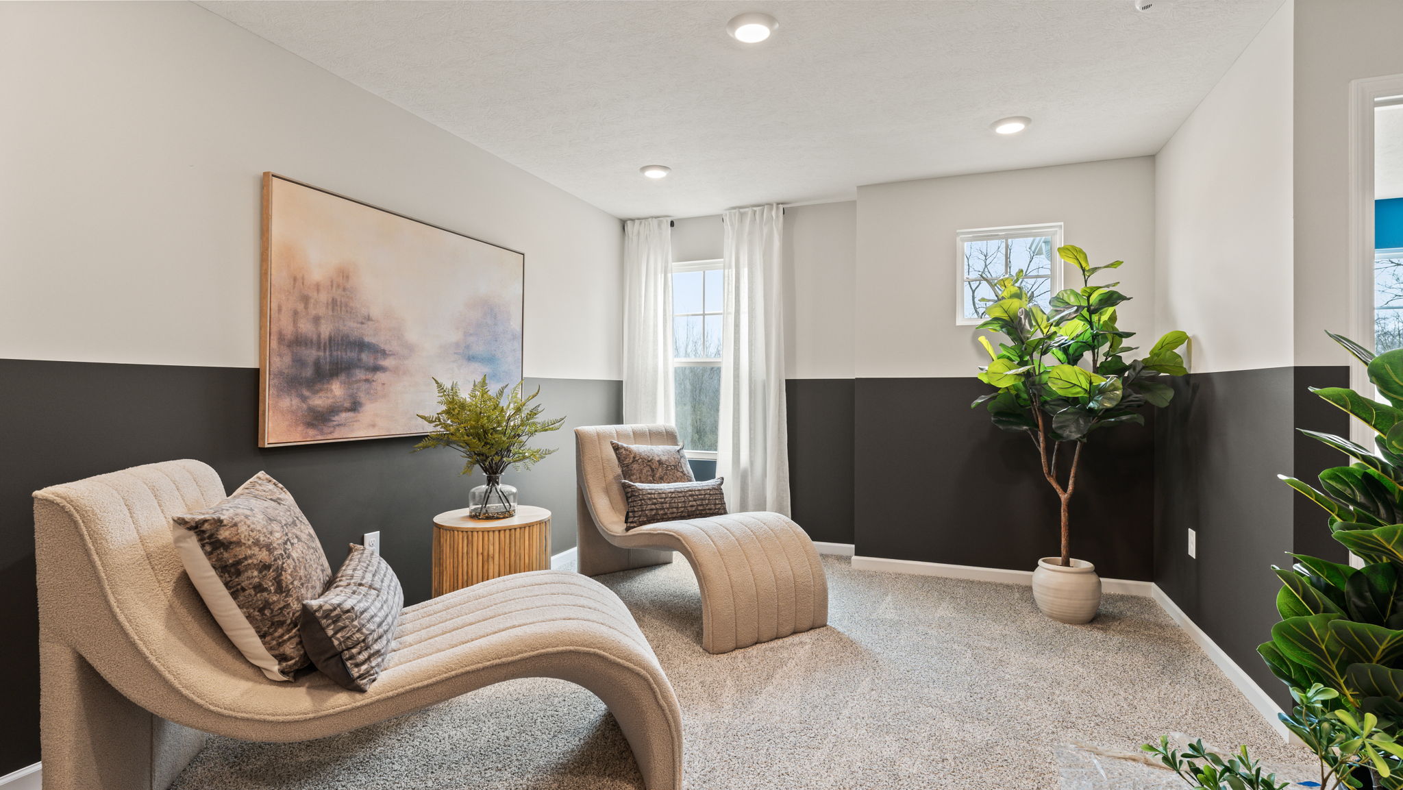 Two-tone black and white walls, laid-back white chairs, and pictures on wall
