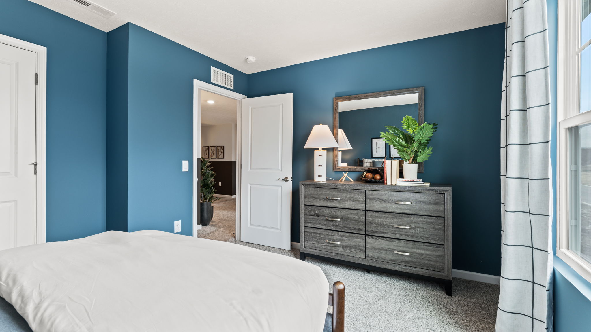 Bedroom 2 from the bedside with blue wall paint and grey dresser drawer