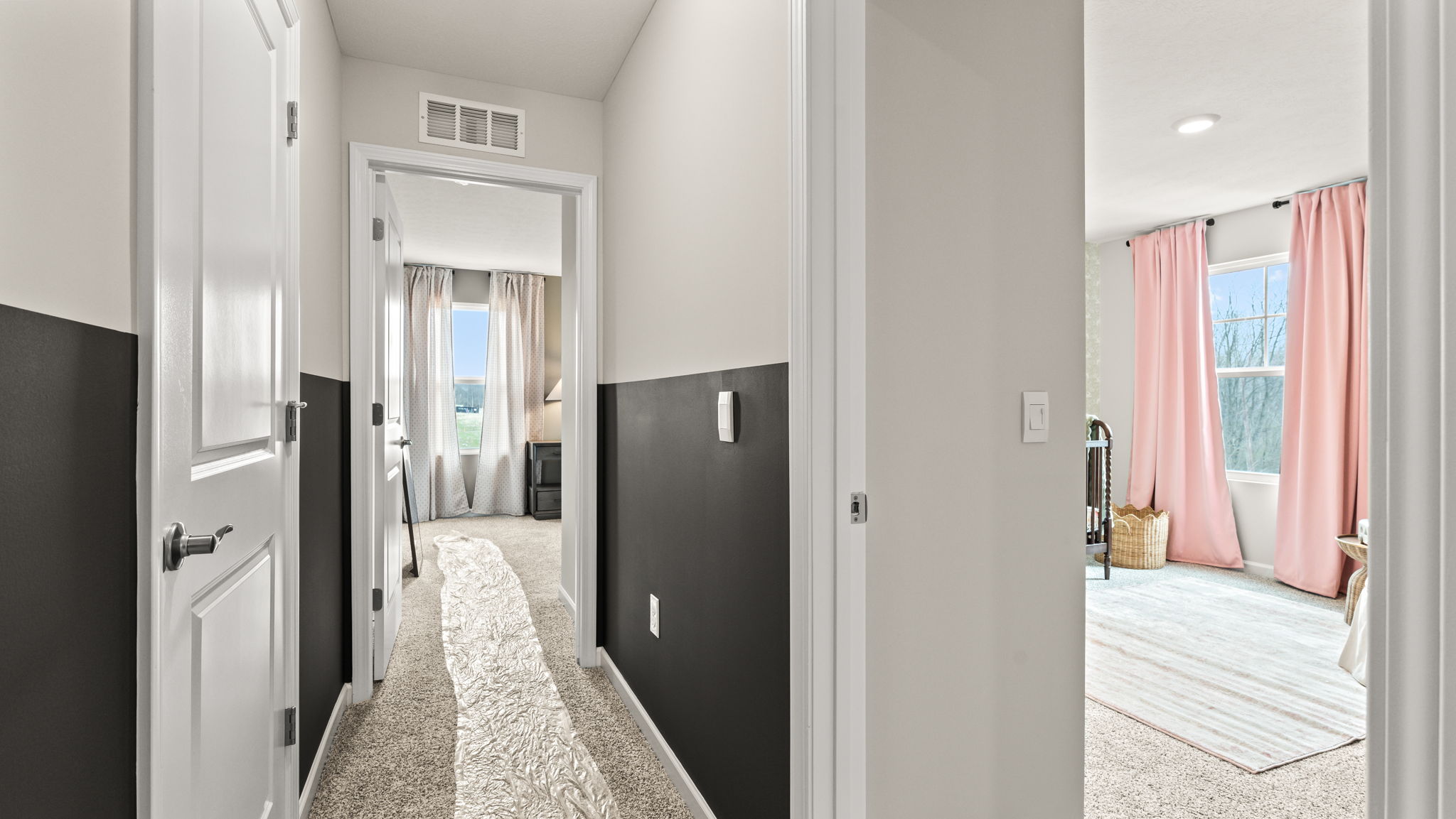 Hallway with doors to two bedrooms with lots of natural lighting