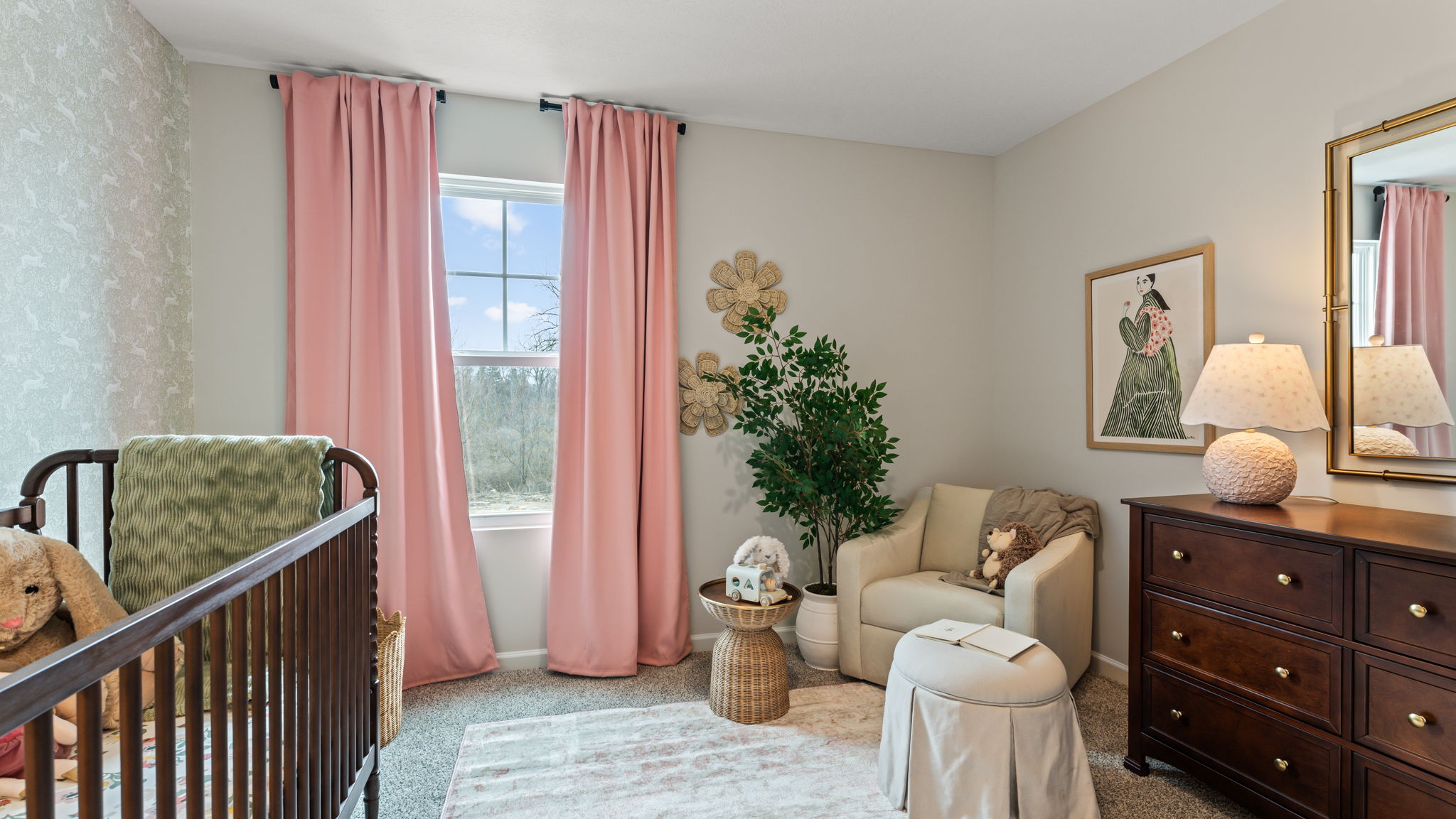 closeup of nursery room crib with soft pink curtains in the back and dresser drawer on the right of frame.