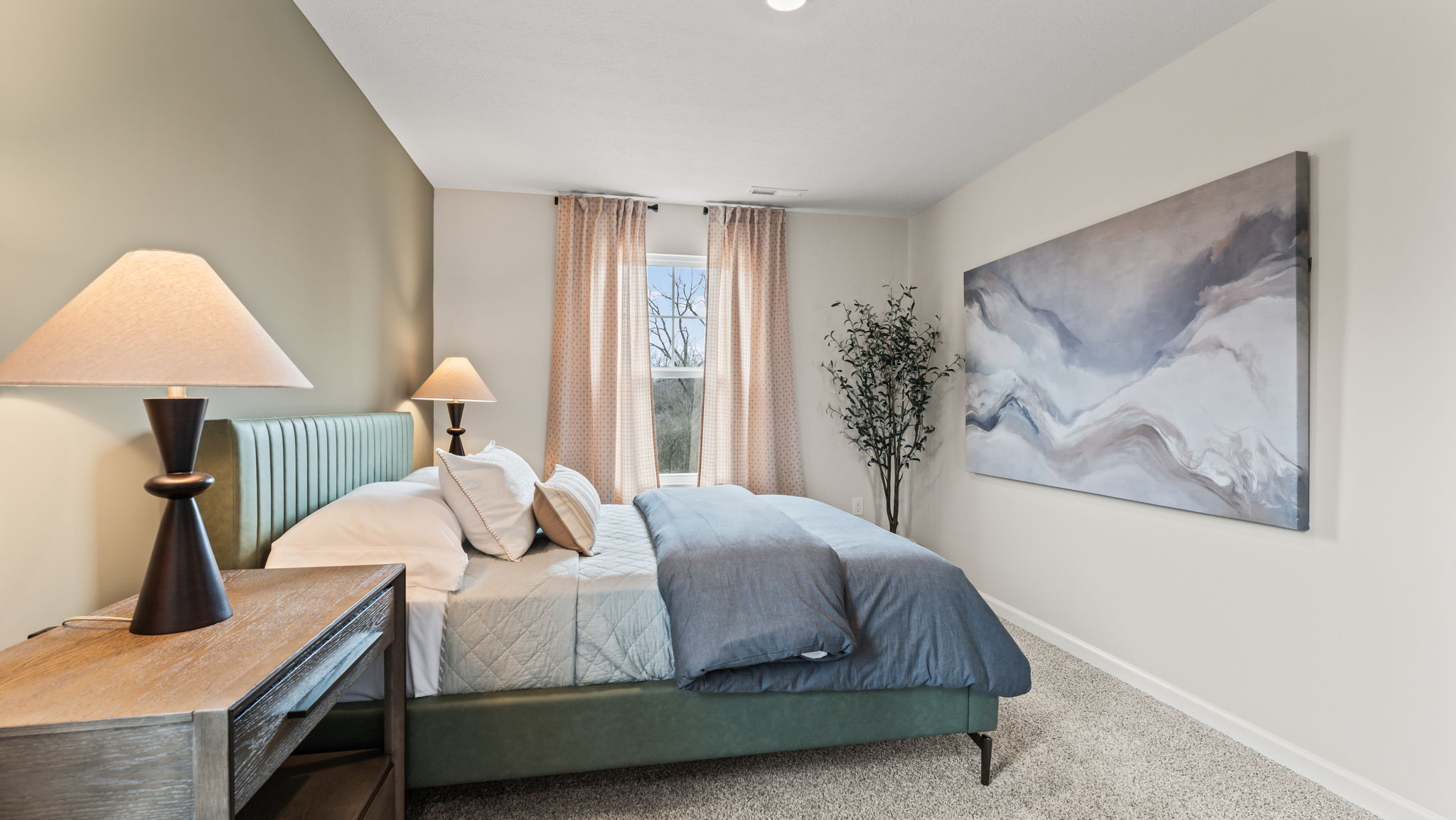 Side view of bed with nightstands on the side of it and blue painting on wall