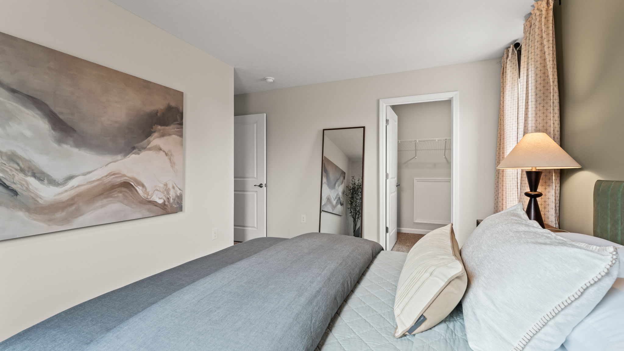 Closeup of bed with closet and mirror in the back