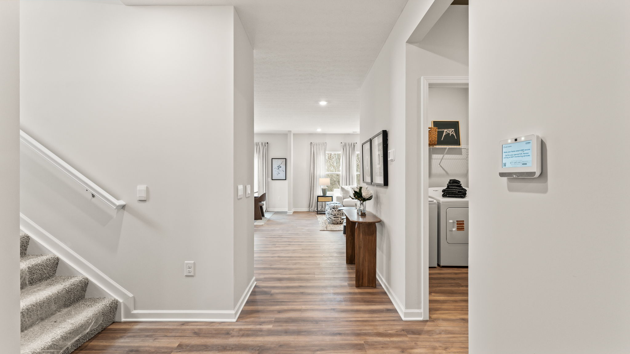 Hallway view of the stairs leading to the second level and on the left and the launry room on the right